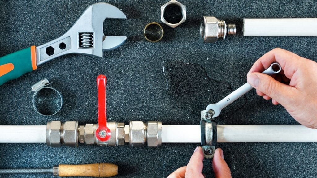 Plumber repairing a pipe valve with an adjustable wrench in Waco