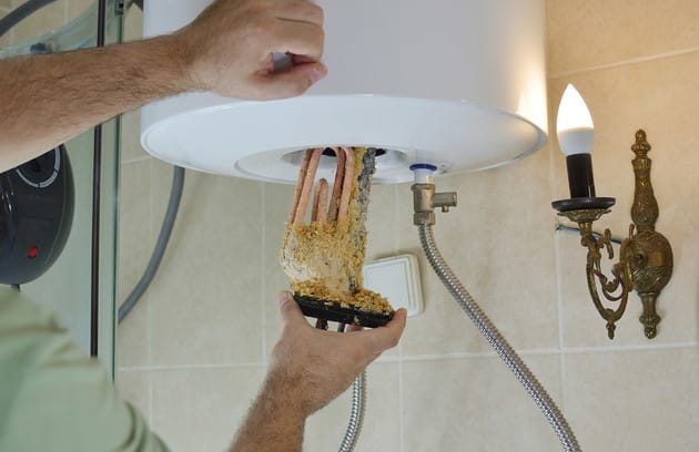 Technician removing mineral buildup from a water heater in Waco