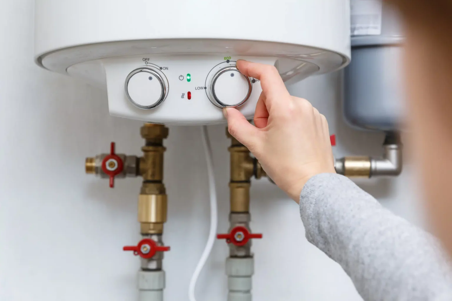 Homeowner adjusting the temperature controls on a water heater in Waco